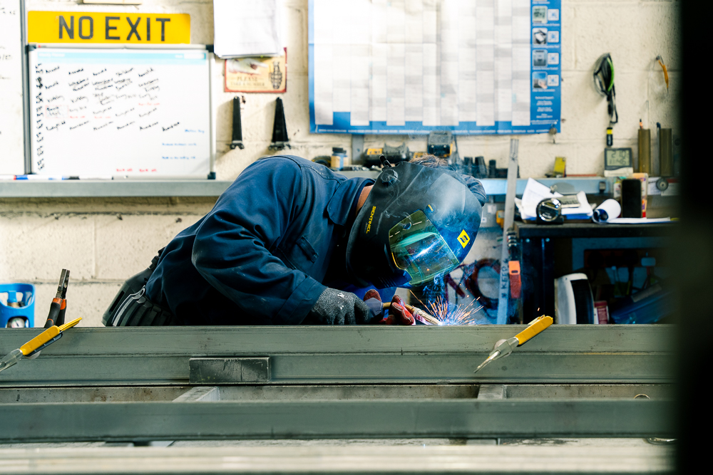 Welder working on metal fabrication in a workshop.