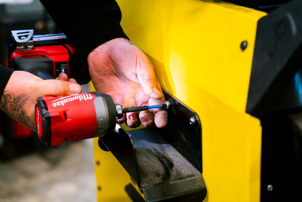 Shropshire Welding Solutions technician using a power tool on metal equipment.